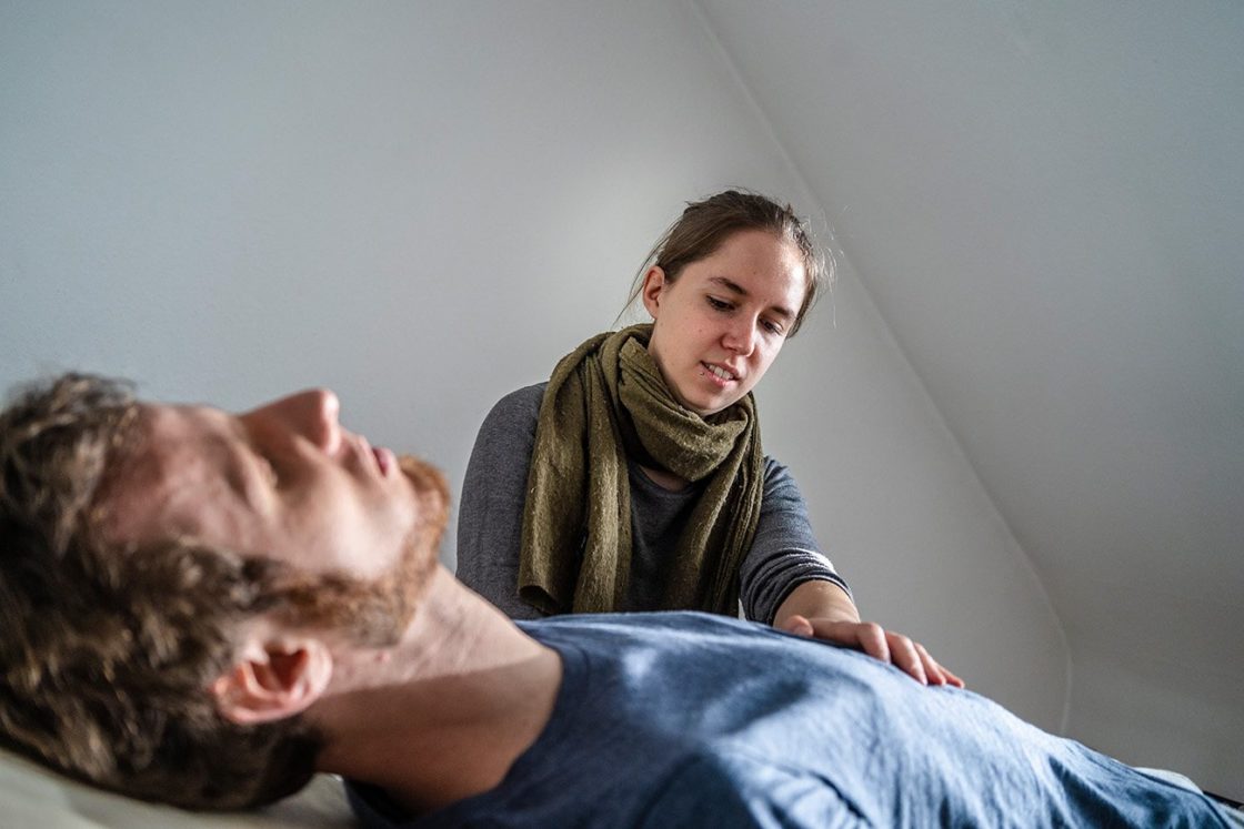 Ansicht Cranio-Sacral-Behandlung: Sophia Heister mit konzentriertem Blick auf Patient, eine Hand dabei auf dem Brustkorb